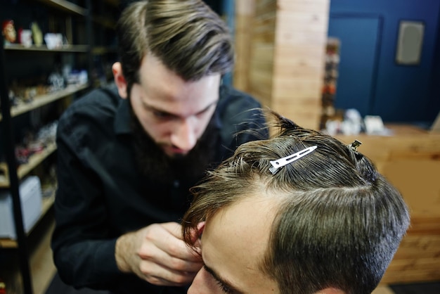 The Barber man in the black shirt in the process of cutting a customer in the barbershop