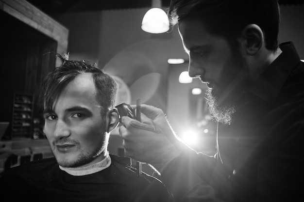 Barber man cutting a client's hair clippers in the barbershop black-and-white photo