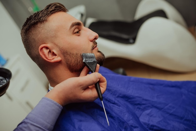 The barber paints the beard and the mustache of the young man in the barbershopSelective focus High quality photo