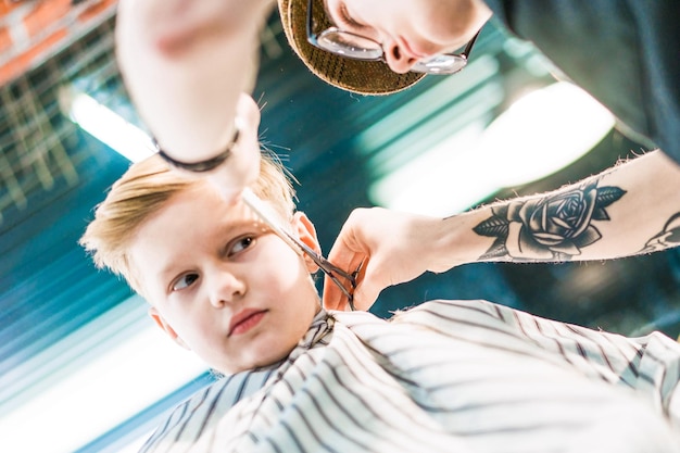 Barber's hands cutting boy's hair with scissors