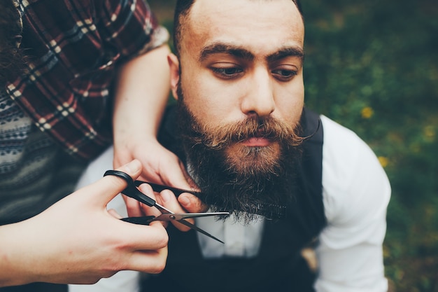 Barber shaves a bearded man in vintage atmosphere