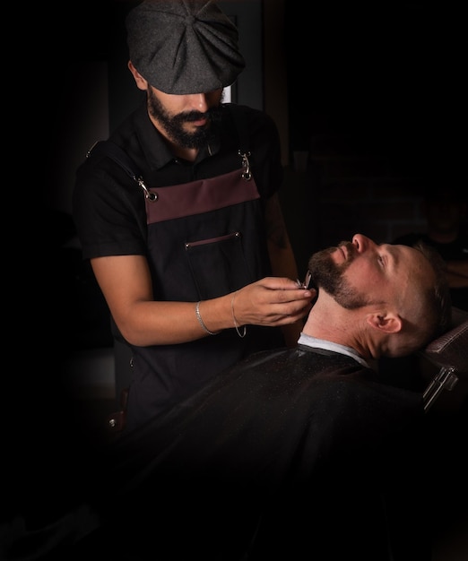 Barber shop barber shaving his client selective focus