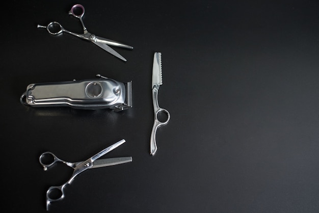 Barber shop equipment on Black background with place for text. Professional hairdressing tools. Comb, scissor, clippers and hair trimmer isolated