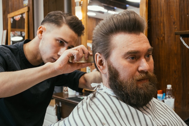 Barber shop, a man with a beard cut hairdresser. Beautiful hair and care, hair salon for men. Professional haircut, retro hairstyle and styling. Customer service. Russia, Sverdlovsk, February 12, 2018