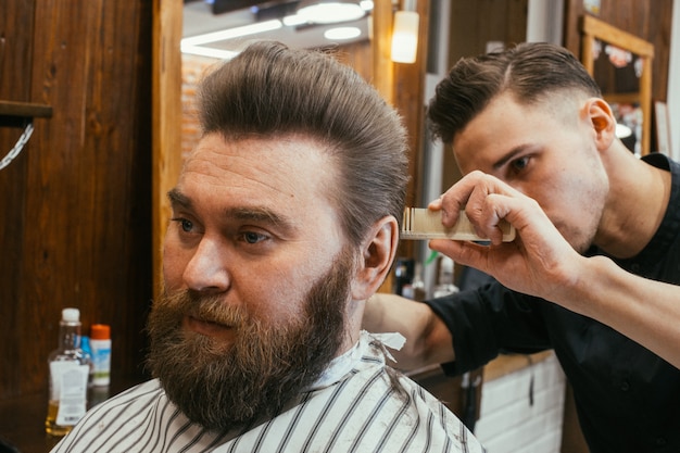 Barber shop, a man with a beard cut hairdresser. Beautiful hair and care, hair salon for men