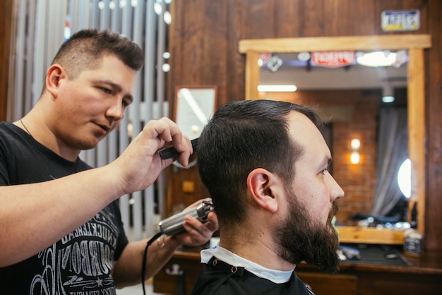 Barber shop, a man with a beard cut hairdresser. Professional haircut, retro hairstyle and styling. Beautiful hair and care, hair salon for men. Customer service. Russia, Sverdlovsk, February 12, 2018