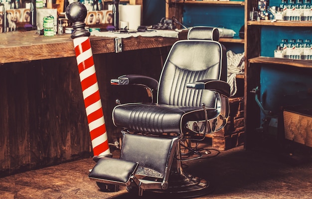 Barber shop pole. Logo of the barbershop, symbol. Stylish vintage barber chair. Hairstylist in barbershop interior. Barber shop chair. Barbershop armchair, barber shop for men.