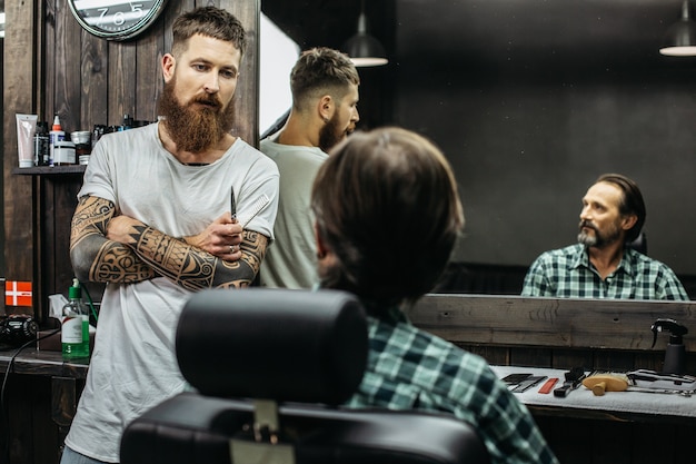 barber standing with comb in his hand and having arms crossed