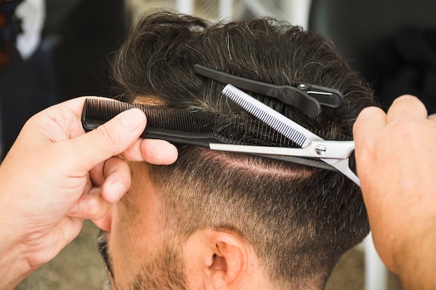 Barber using scissors and comb to cut the man's hair