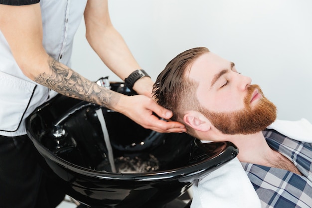 Barber washing head client in barbershop