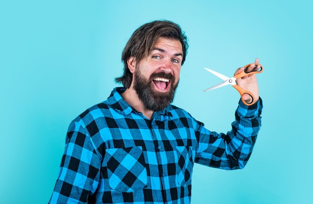 Barbershop concept bearded man in checkered shirt cut hair casual guy use barber tool happy hipster with long hair and moustache hold scissors male beauty and fashion