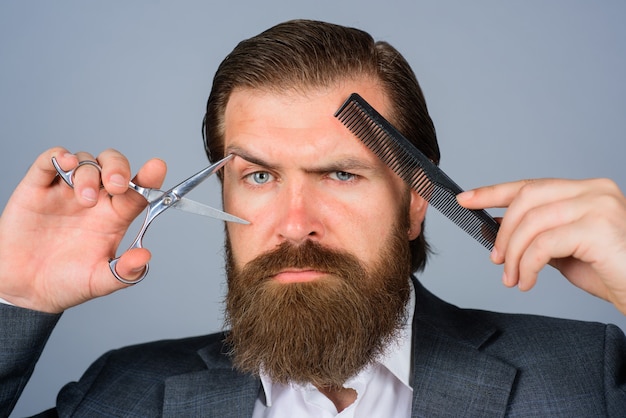 Barbershop handsome bearded man with hairdresser or barber tools professional beard care hairdresser