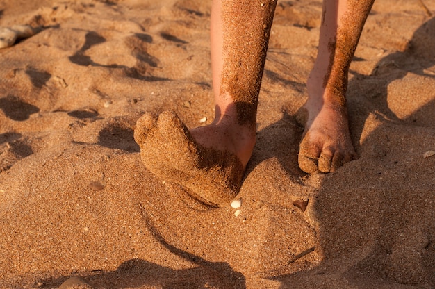 Bare feet of a child in the sand on the beach