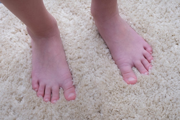 Bare feet of a man on a warm fluffy beige carpet