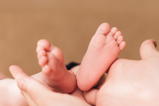 Bare feet of a newborn baby in a grey pants, selective focus