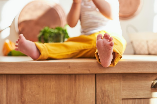 Barefoot baby leg in yellow pants closeup