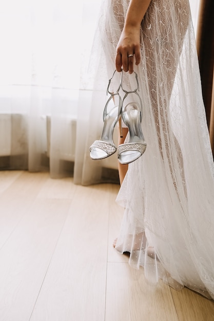 Barefoot bride holding wedding shoes