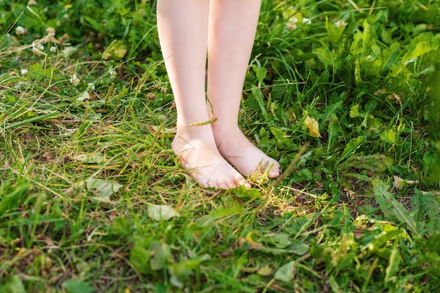 Barefoot of child standing on green grass.