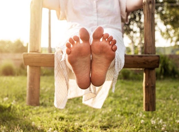 Barefoot girl in swings on summer holiday close up