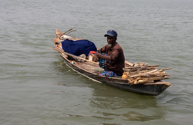 Barisal Bangladesh March 12 2023 A fisherman catching fish on a small dinghy floating on a river Beautiful Southeast Asian fisherman daily life Old fisherman fishing on the river with a boat