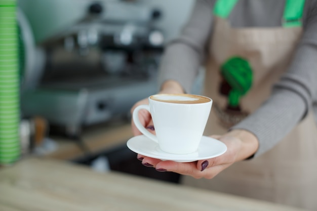 Barista in apron in coffee shop give just brewed fresh coffee to customer