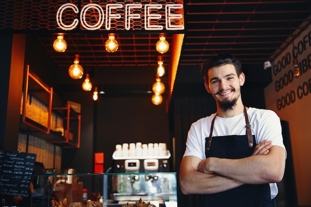 Barista in apron wearing face mask standing at the bar of the coffee shop