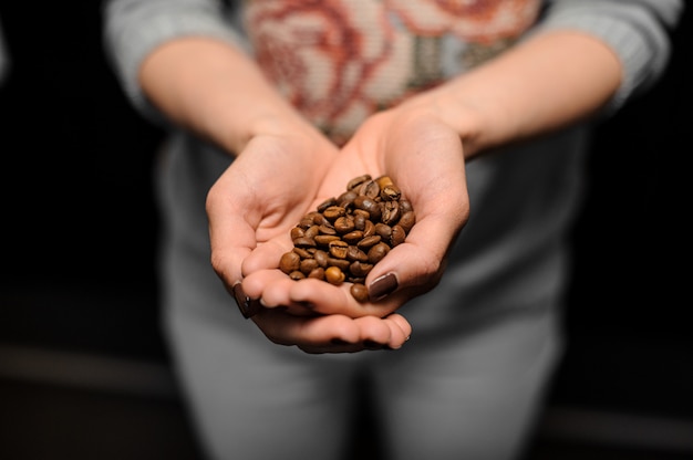 Barista girl holding in her hands a small handful of coffee grains