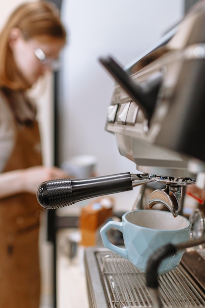 A barista girl pouring coffee from a coffee machine into a cup Cafe