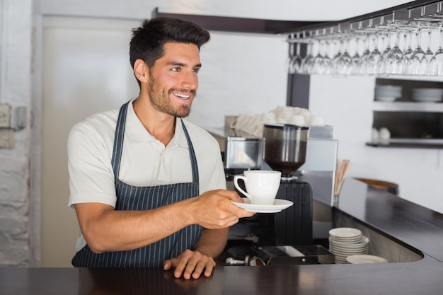 Barista holding cup of coffee at the cafÃ©