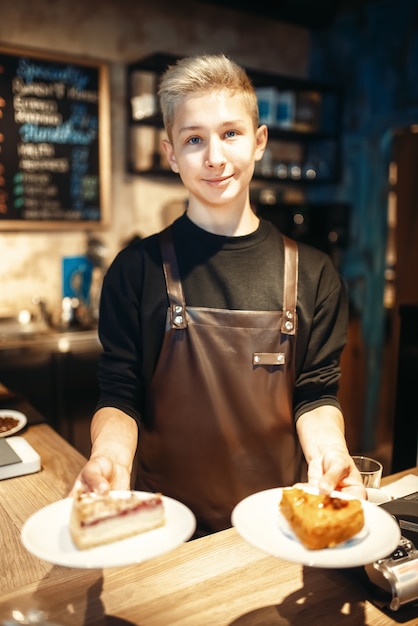 Barista holding in hands plates with sweet dessert