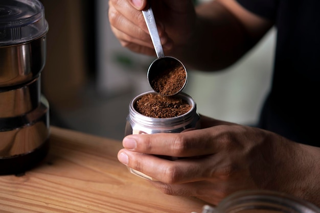 Barista holding moka pot with ground coffee in coffee shop