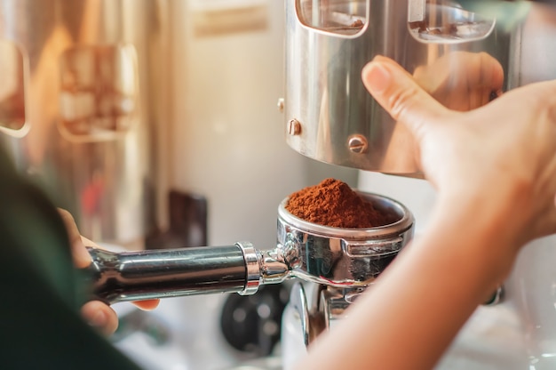 Barista holding tamper of pressing ground coffee making