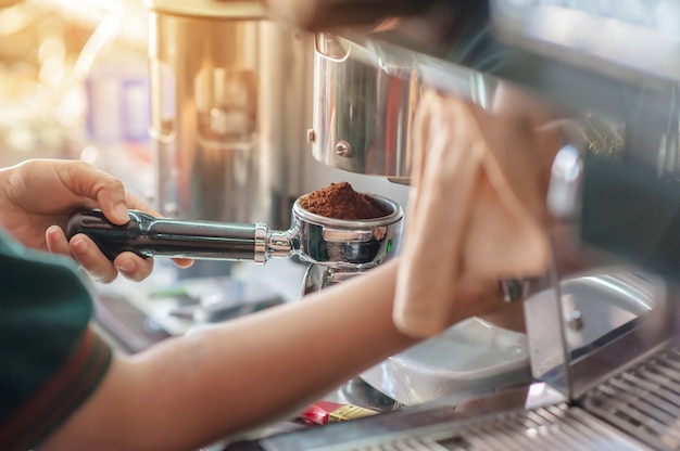 Barista holding tamper of pressing ground coffee making