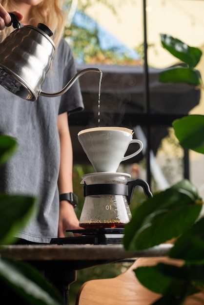 Barista is making drip brewing filtered coffee or pour over coffee with hot water and filter paper in coffee shop