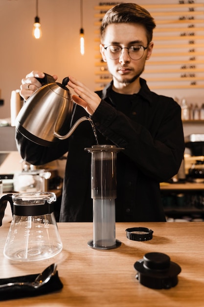 Barista is pouring hot water from drip kettle to aeropress Process of brewing aeropress Pouring hot water over roasted and ground coffee beans in aeropress