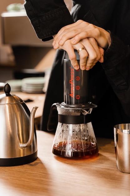 Barista is pushing aeropress for pouring coffee drops trought aeropress to pot Alternative scandinavian coffee brewing method Aeropress coffee