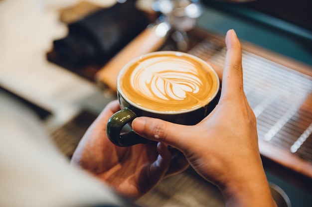 Barista making latte art, shot focus in cup of milk and coffee