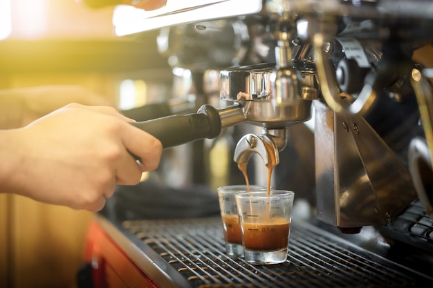 Barista making perfect shots of coffee on coffee machine