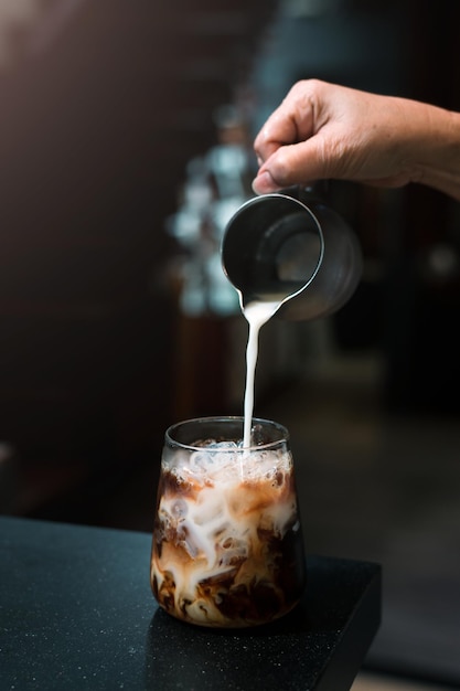 Barista pouring milk in glass