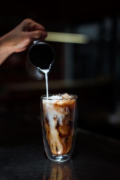 Barista pouring milk in glass