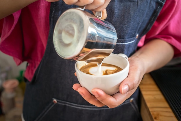 Barista pouring milk into coffee making a cappuccino Barista making cappuccino