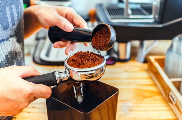 Barista pours coffee bean roaster powder ground coffee pouring into a portafilter make coffee