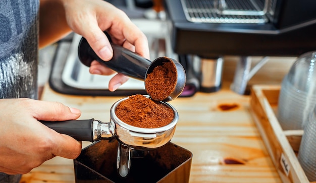 Barista pours coffee bean roaster powder ground coffee pouring into a portafilter