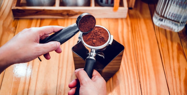 Barista pours coffee bean roaster powder ground coffee pouring into a portafilter