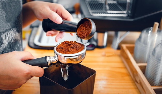 Barista pours coffee bean roaster powder ground coffee pouring into a portafilter