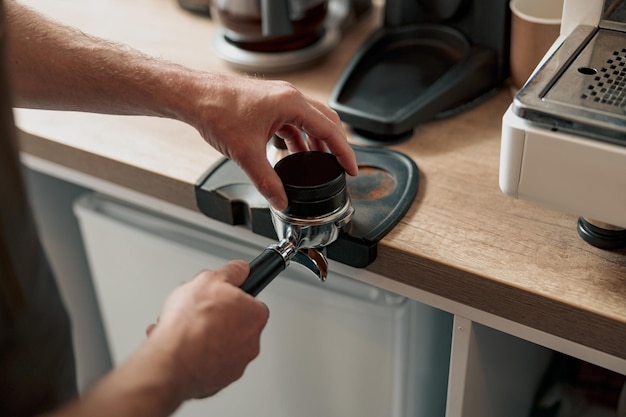 Barista pressing ground coffee into portafilter with tamper