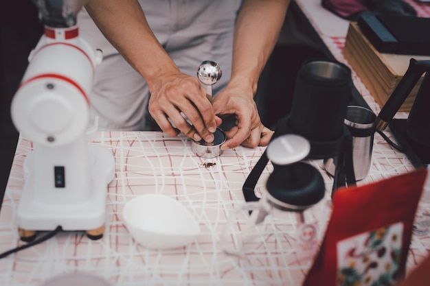 Barista pressing ground coffee with tamper preparing coffee in cafe