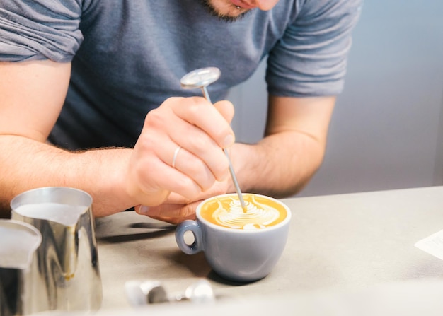 Barista using coffee machine preparing fresh coffee or latte art and pouring into white cup at coffee shop and restaurant bar or pub