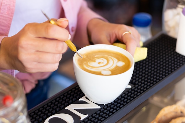 Barista woman draws a bear on coffee foam in cafe. Close-up. Latte art.