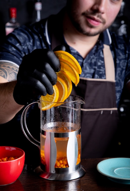 Barman adds sliced orange to tea close-up